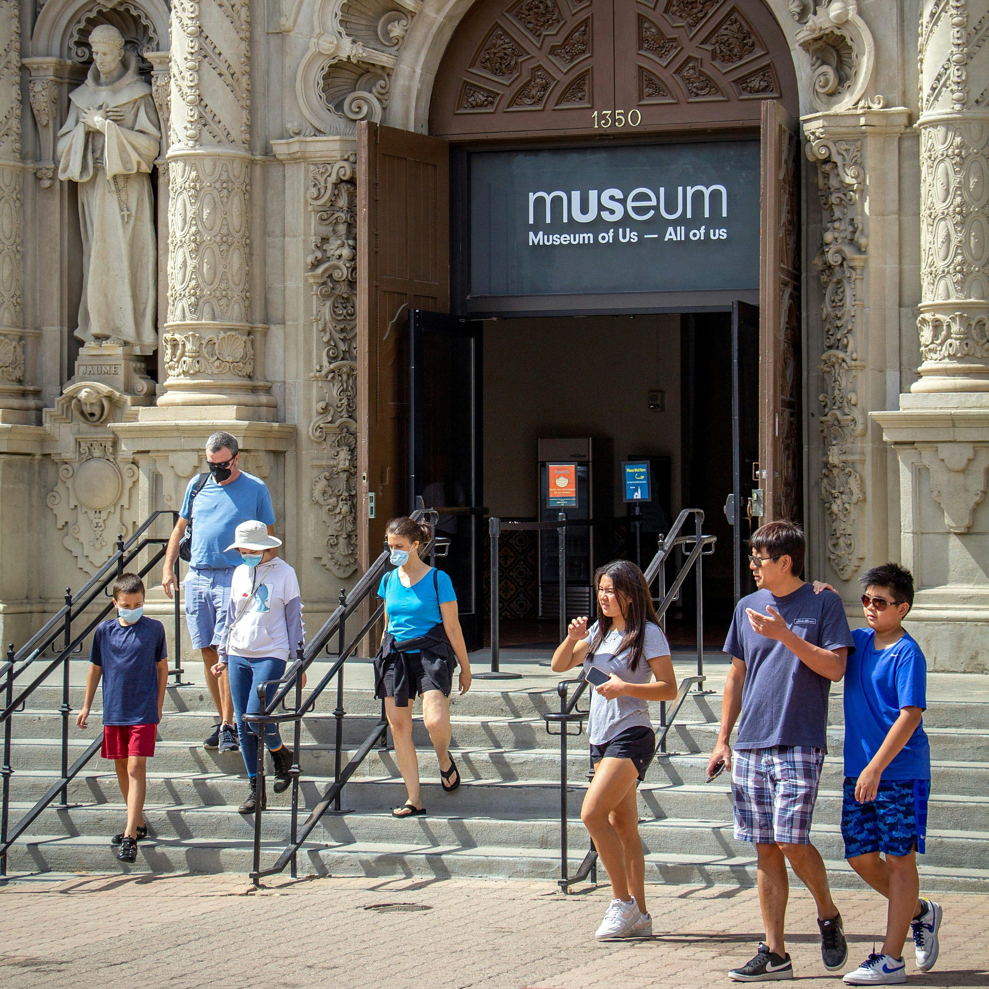 Two separate families walking by the Museum entrance and down the front steps.