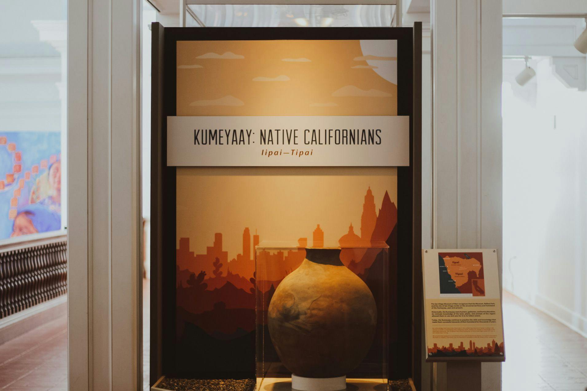 Title wall of the exhibit featuring a large pot before an animated natural landscape with text that reads, "Kumeyaay: Native Californians - Iipai-Tipai"