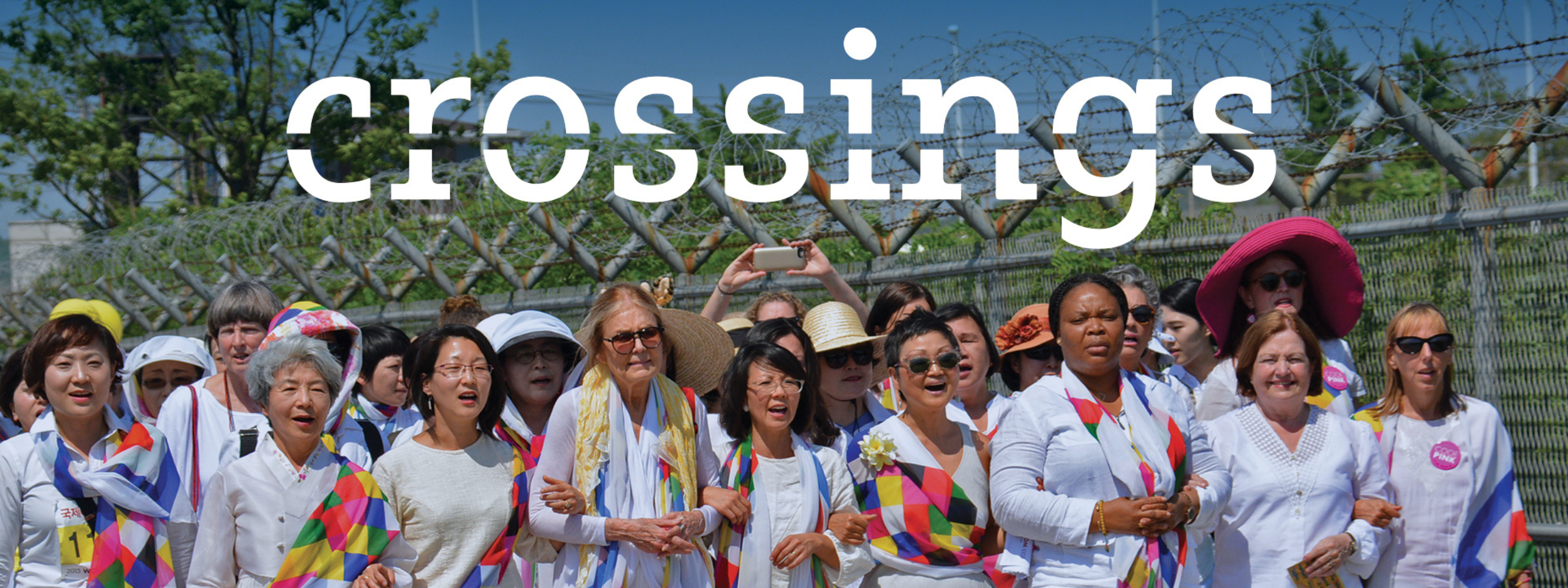 Image from the Crossings documentary featuring a group of several women walking together with their arms interlocked during a peaceful protest march. 