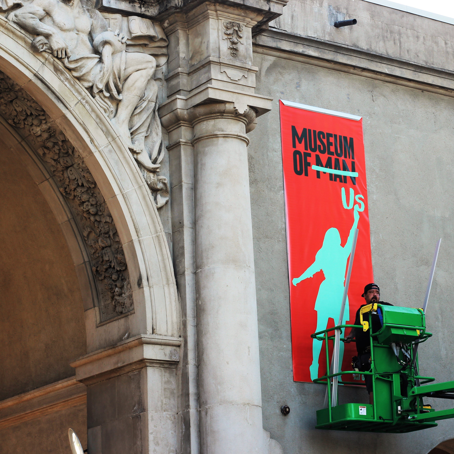 Person installing signage outside the museum announcing the museum's name change.