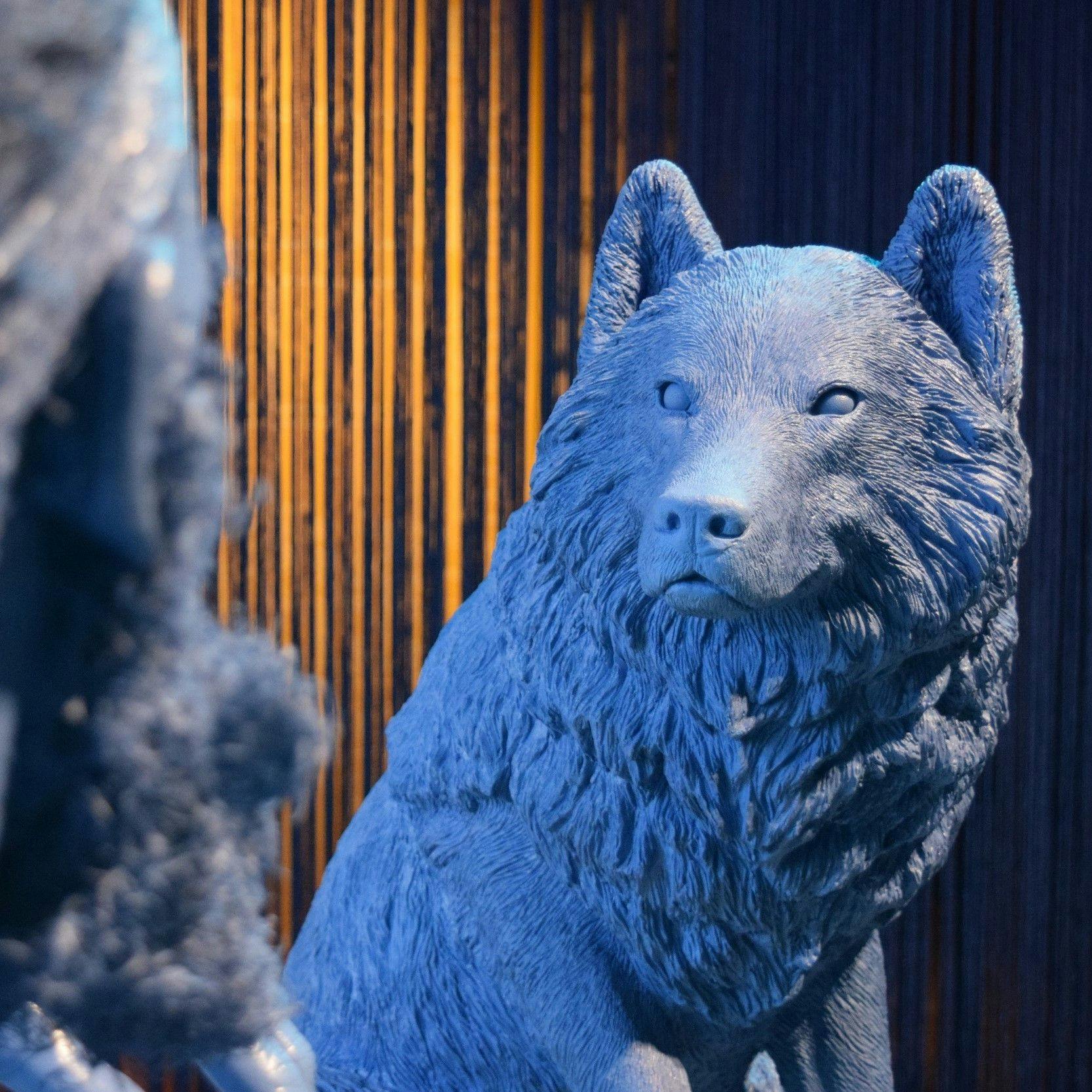 Blue, detailed model of a wolf looking towards a blue model of a human with a beard.